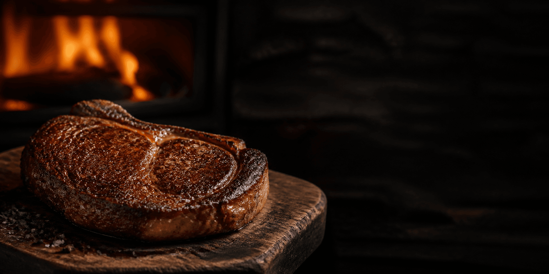 Seared dry-aged ribeye steak with open flame in the background